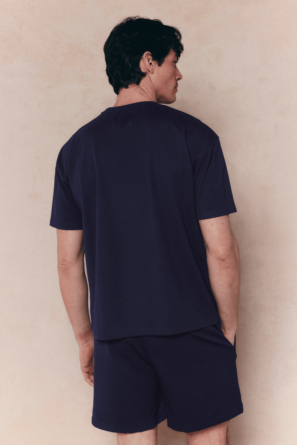 Man wearing a navy Tomas elasticated waist short and matching t-shirt, shown from behind.