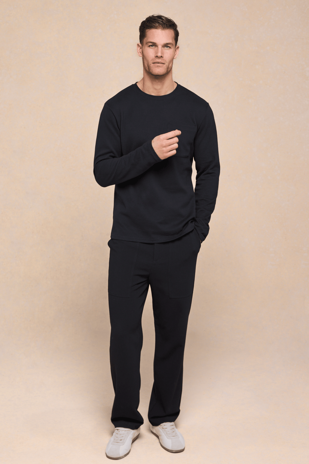 Man wearing a black Tyler long sleeve crew neck t-shirt with a chest pocket and matching black pants.