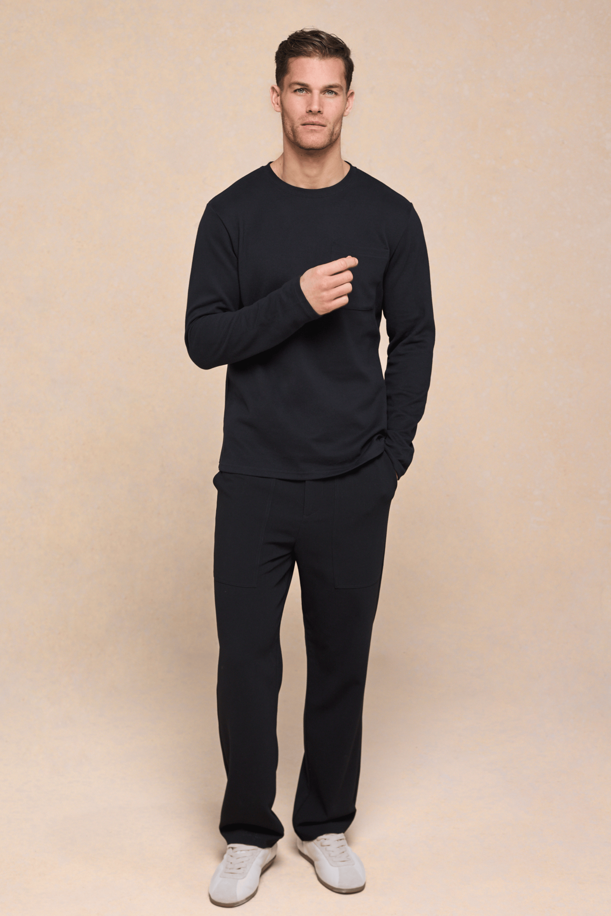 Man wearing a black Tyler long sleeve crew neck t-shirt with a chest pocket and matching black pants.