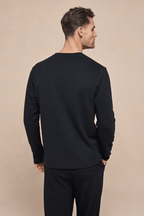 Man from behind wearing a black Tyler long sleeve crew neck t-shirt with a chest pocket.