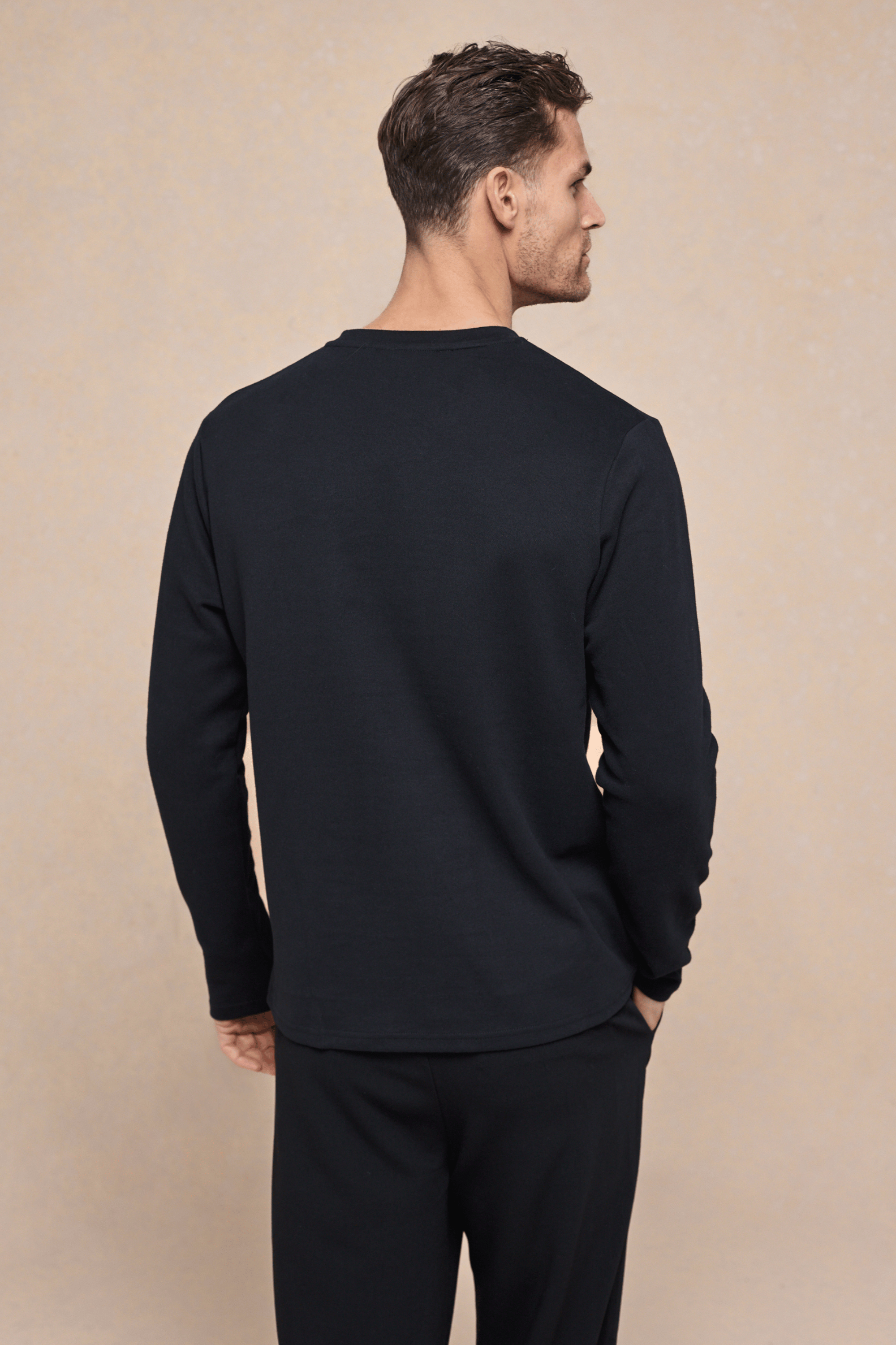 Man from behind wearing a black Tyler long sleeve crew neck t-shirt with a chest pocket.