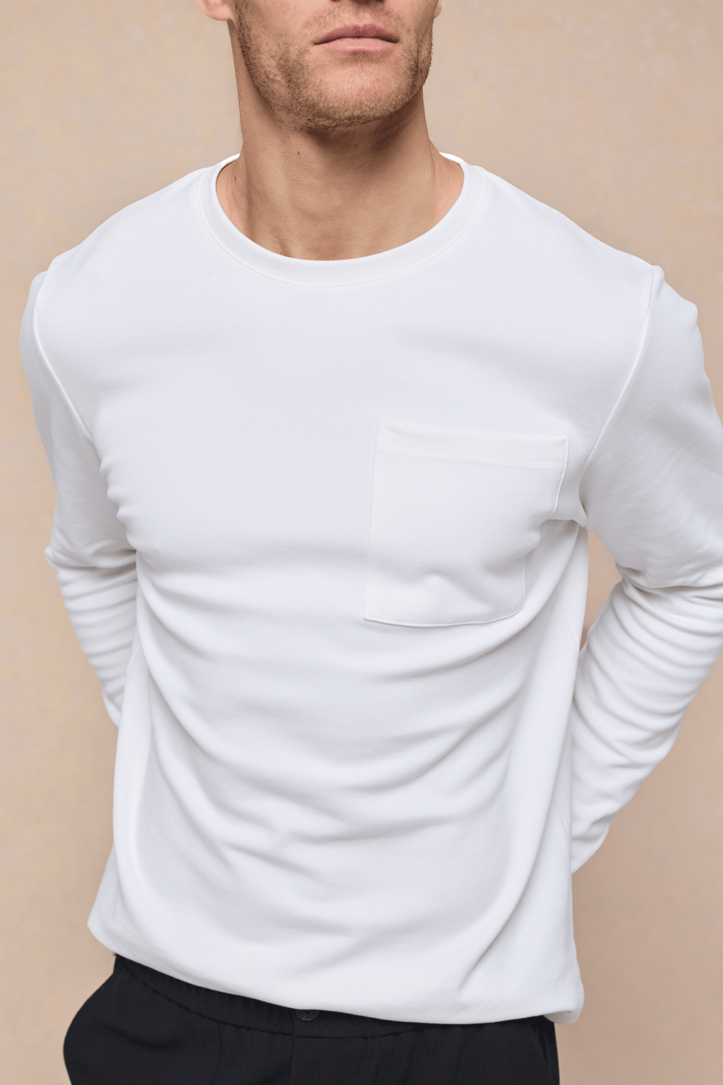 Man wearing an ecru long sleeve crew neck t-shirt with a chest pocket.