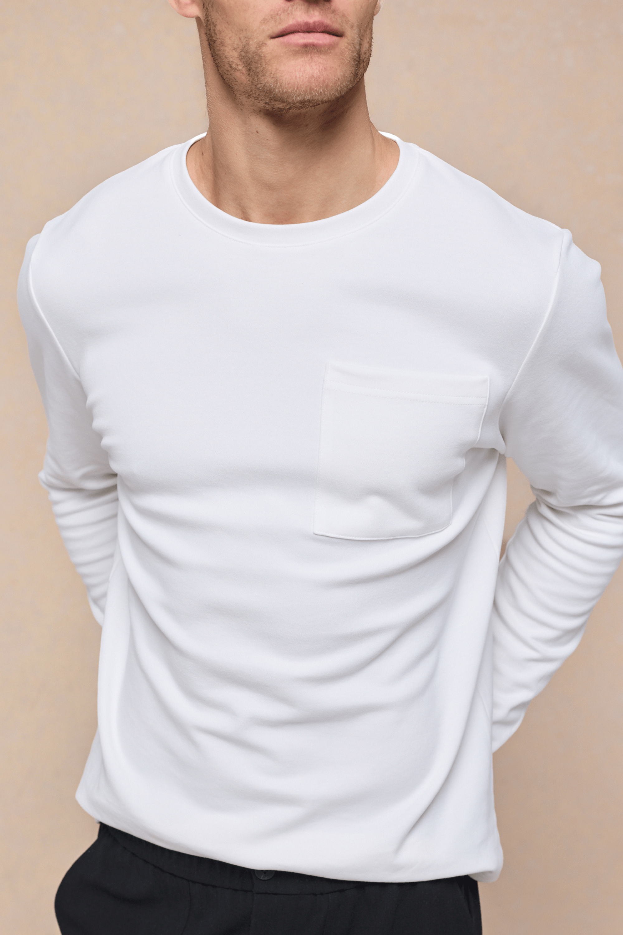 Man wearing an ecru long sleeve crew neck t-shirt with a chest pocket.