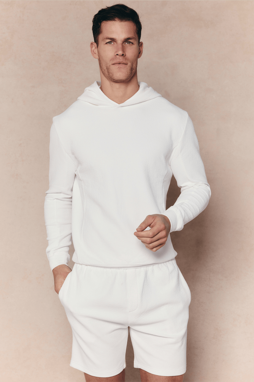 Man wearing an ivory Zarco Crinkled Jersey Hoodie and matching shorts.