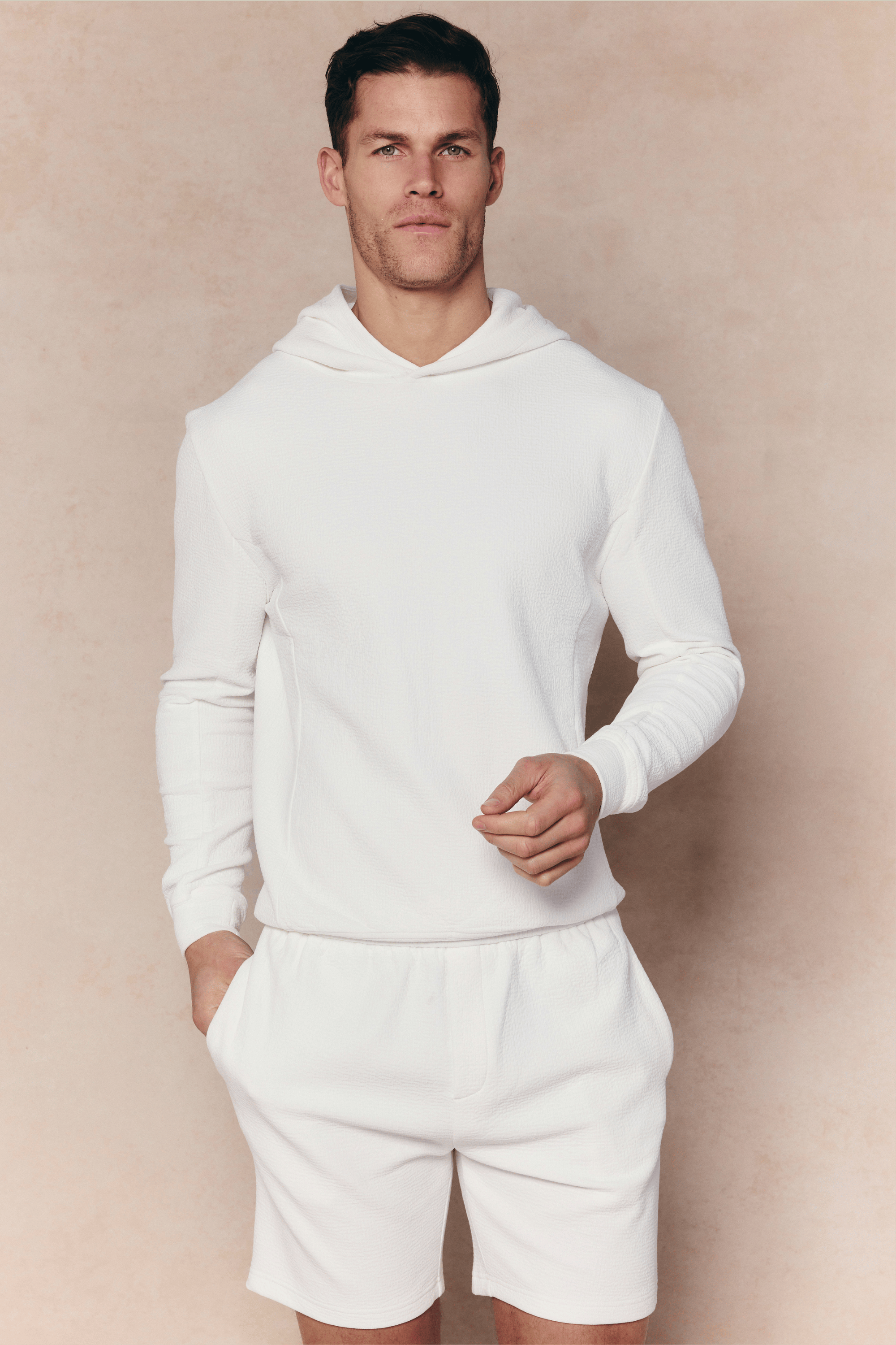 Man wearing an ivory Zarco Crinkled Jersey Hoodie and matching shorts.