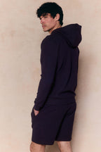 Man in navy Zarco Crinkled Jersey Hoodie and matching shorts, looking over his shoulder.
