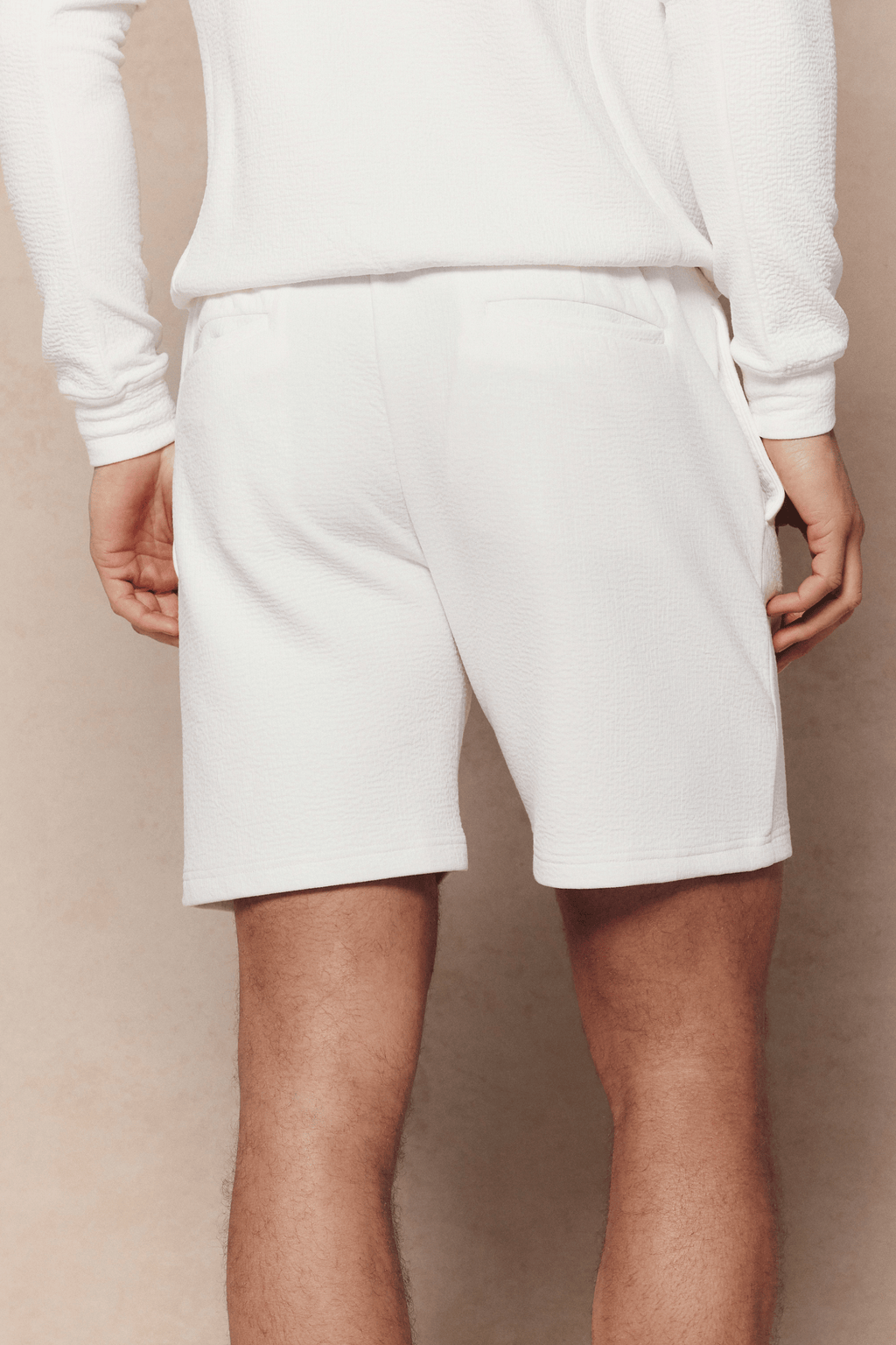 Rear view of a person wearing ivory Zarco crinkled jersey shorts with a matching long-sleeve top.