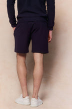 Man wearing navy Zarco crinkled jersey shorts and matching long-sleeve top, with hands in pockets.